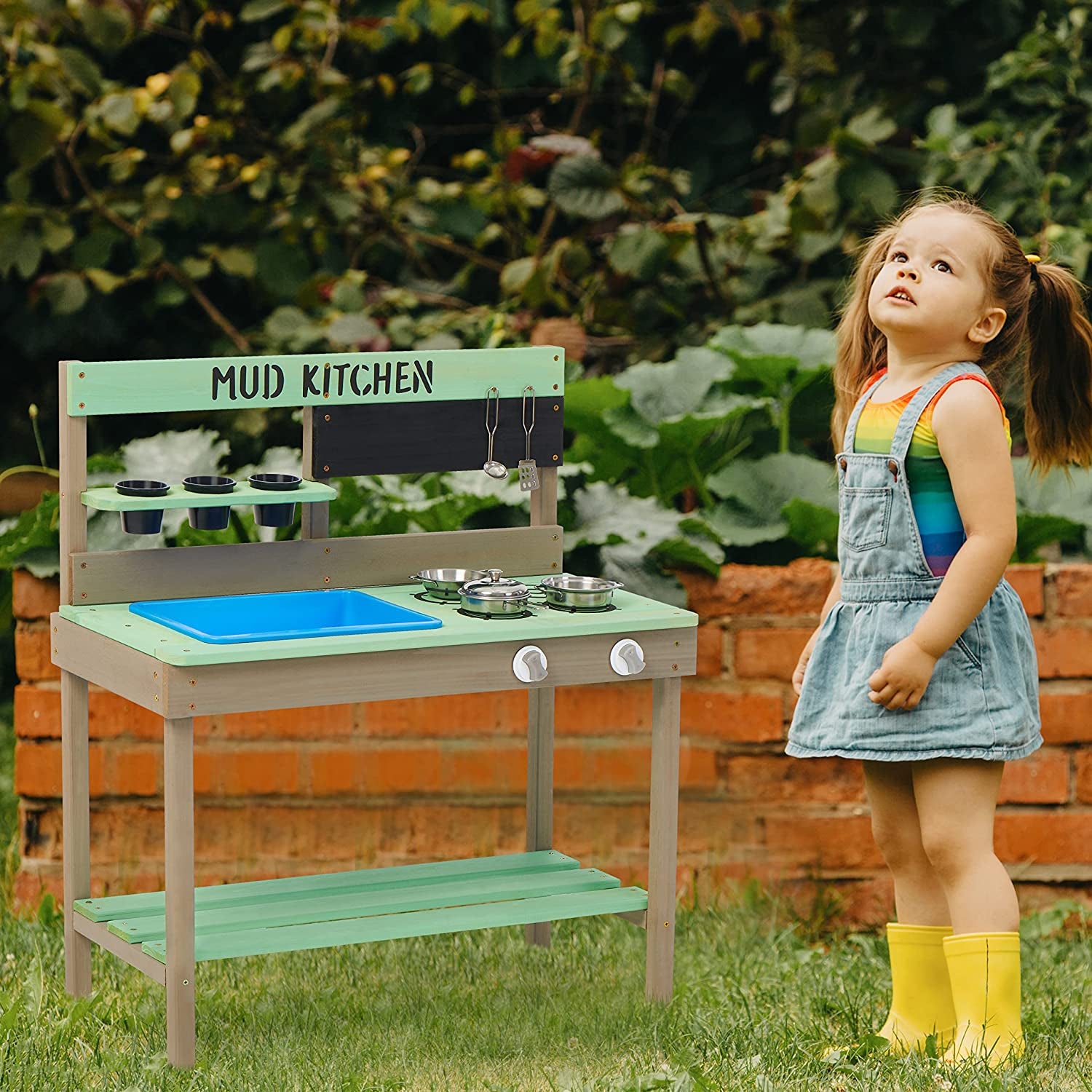 child standing outside beside mud kitchen with stove and faux slop sink