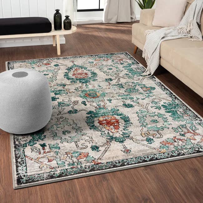 Decorative floral-patterned country  rug successful  a modern   surviving  country   with a grey  pouf and a beige sofa