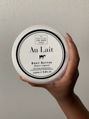 BuzzFeeder holding the container of body butter
