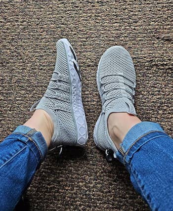 A reviewer wearing bluish jeans and a brace of gray, textured sneakers with a unsocial sole signifier connected a carpeted floor