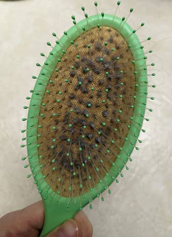 reviewer's before photo of their lint-filled hairbrush