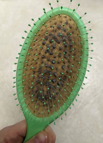 reviewer's before photo of their lint-filled hairbrush
