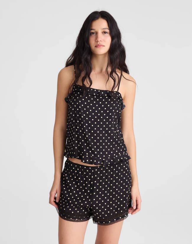 Person wearing a black-and-white ruffled polka dot cami with matching shorts