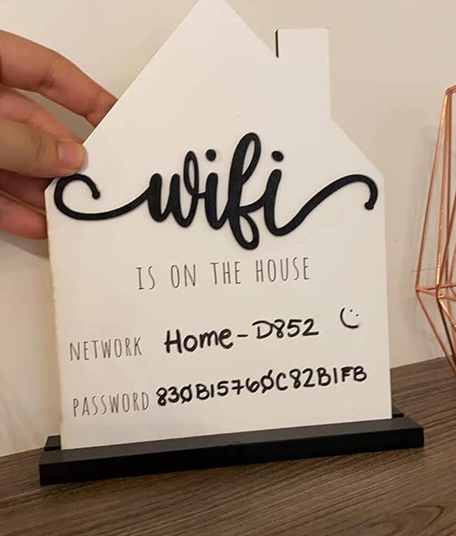 closeup of house shaped wooden sign with wifi info placed on reviewer's mantel 