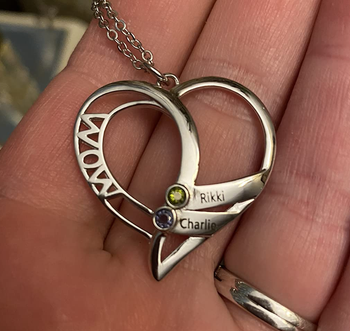 Reviewer holding the silver heart necklace with two names on it 