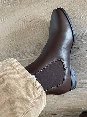 Person wearing a brown Chelsea boot with elastic side panels