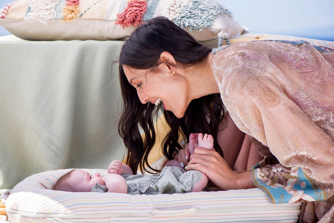 a mom smiling at a baby in a striped dockatot