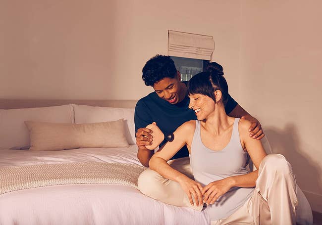 couple in bed using the massager on an arm