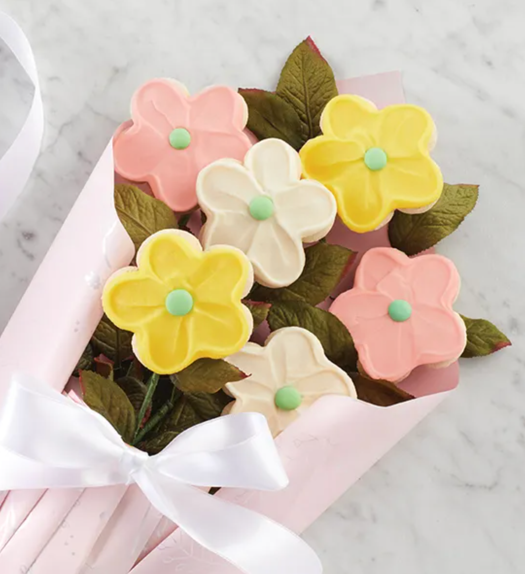 white, yellow, and pink frosted cookies made to look like flowers in a bouquet