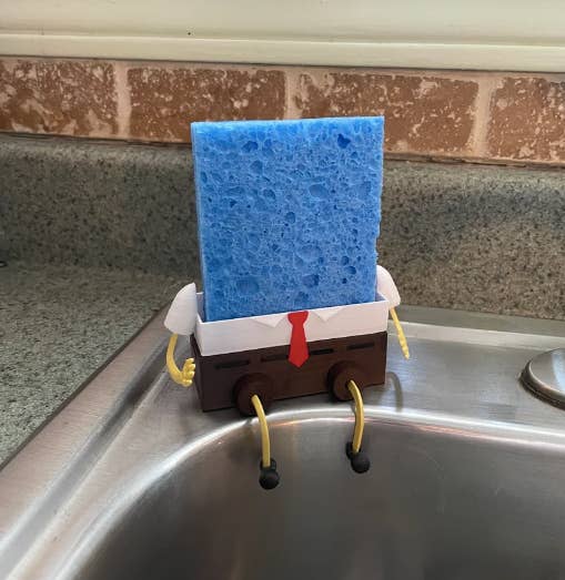 sponge upright in holder with spongebob squarepants body arms and legs sitting on edge of sink