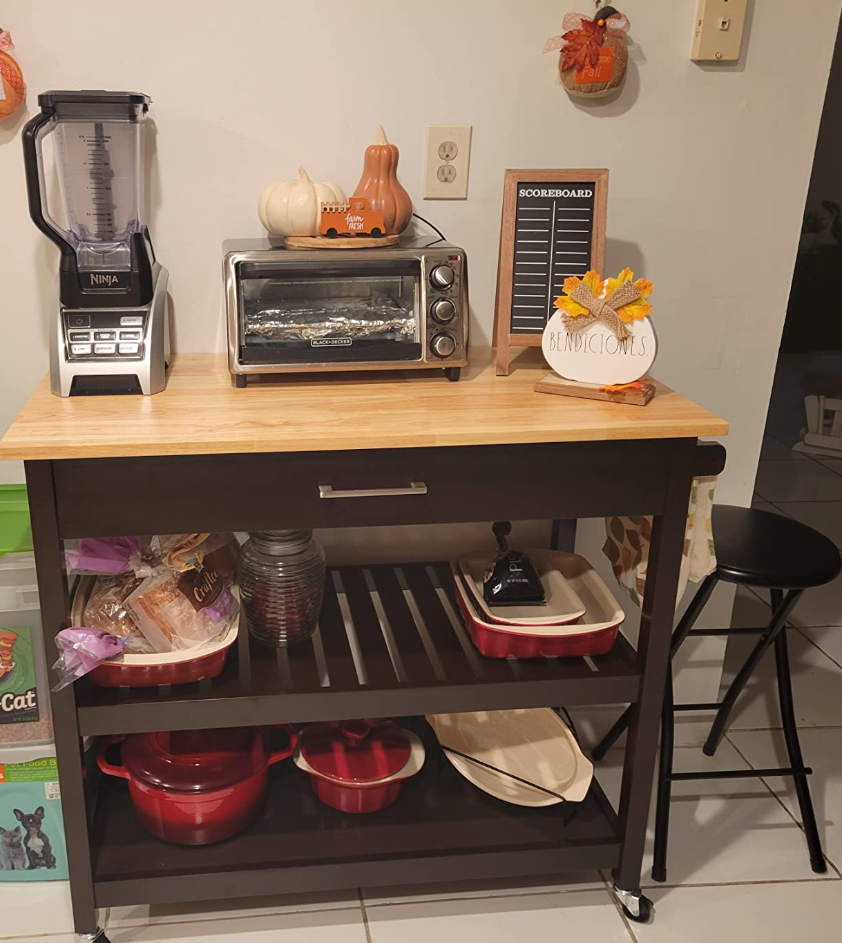 Reviewer image of black and light wood microwave cart in kitchen with pots, food, blender, and toaster oven on shelves