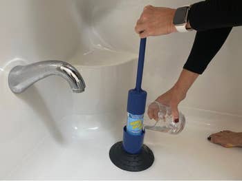 hands using the system on a tub drain, with the long handle attached