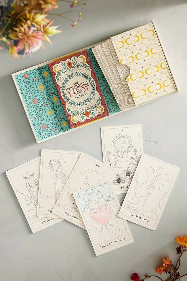 Tarot card deck set with floral designs, featuring cards like Ace of Cups and Three of Swords, laid out for shopping display