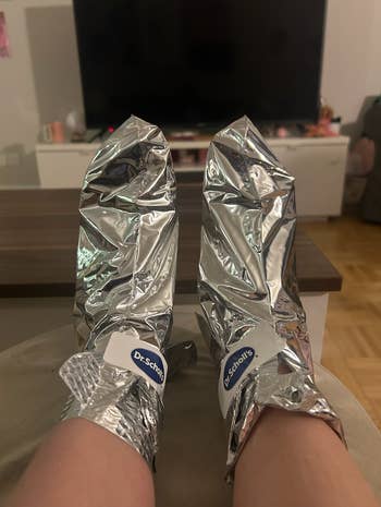 Toes propped up with two metallic foot masks on them 