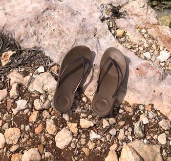 reviewer photo of the brown fitflops on a cliff overlooking water