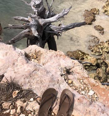 reviewer photo of the brown fitflops on a cliff overlooking water