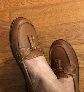 Brown leather loafers with bow item worn connected a woody floor