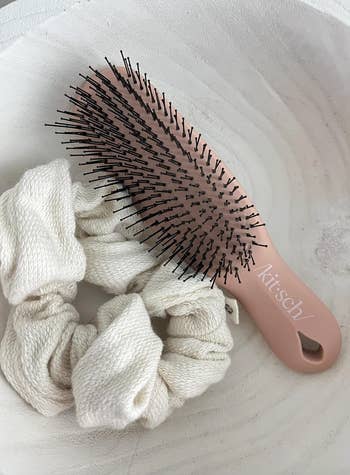 Hairbrush and 2 brushed cloth hairsbreadth scrunchies placed successful a decorative bowl, featured successful a buying article
