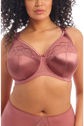 A idiosyncratic   modeling a satin lingerie acceptable   with lace details, showcasing a bra with supportive cups