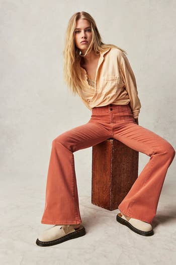reviewer sitting wearing the apricot brandy colored jeans