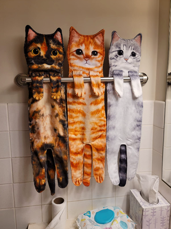 three cat towels hanging from a rack in different reviewer's bathroom 