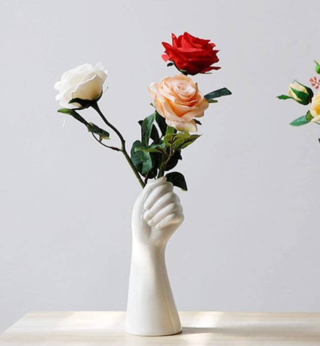 ceramic white vase shaped like a hand holding a bouquet of flowers