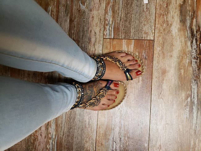 reviewer wearing the sandals with beaded ankle straps and butterfly beads across the foot