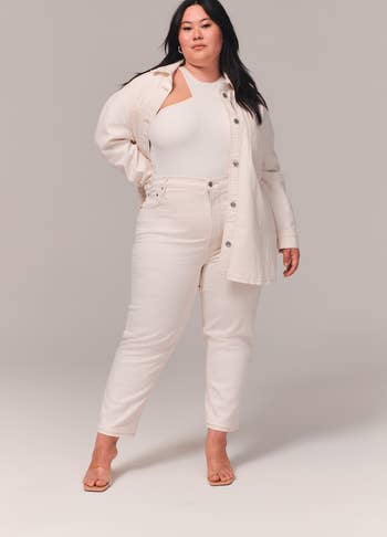 A model posing in the white jeans with a matching jacket