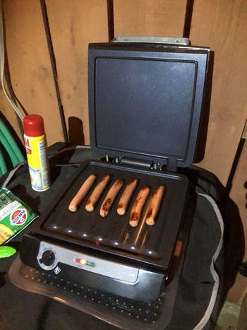 reviewer image of the griddle open and grilling hot dogs