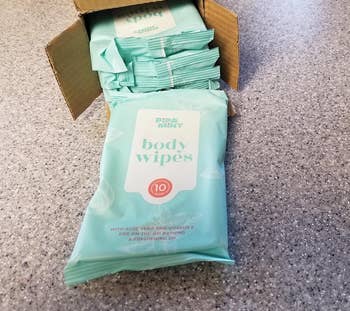 Package of body wipes on a counter with an open box full of more wipes in the background