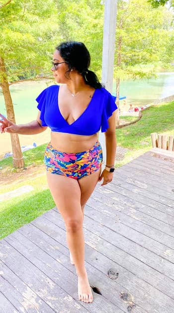 a reviewer wearing a blue top with tropical floral bottoms