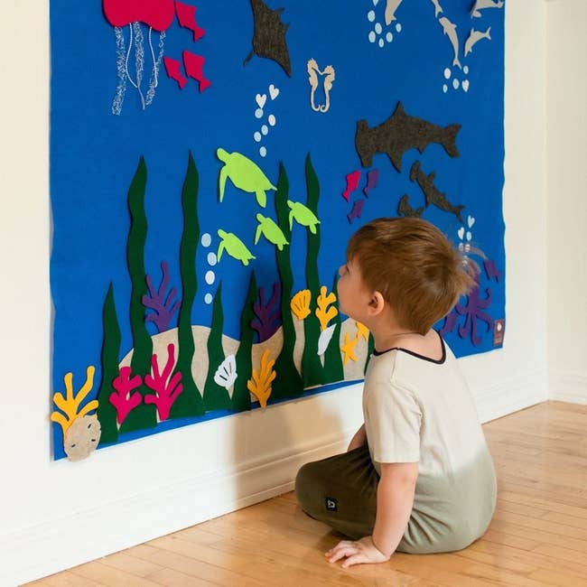 a child playing with a felt wall that looks like an ocean floor
