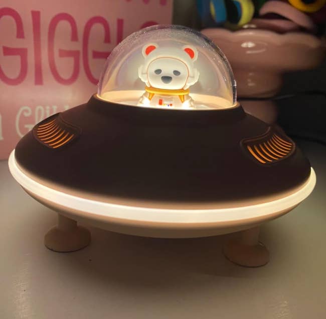 Toy carnivore astronaut wrong a small, dome-covered spaceship exemplary displayed connected a table