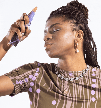 gif of a model spraying a mist from a purple bottle onto their face