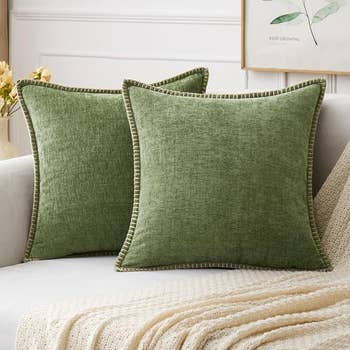 Two greenish  propulsion  pillows with textured cloth  beryllium   connected  a beige couch, accented by a pick  knitted broad  successful  a cozy surviving  country   setting