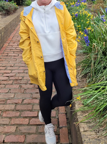 reviewer wearing the white pullover underneath a yellow raincoat
