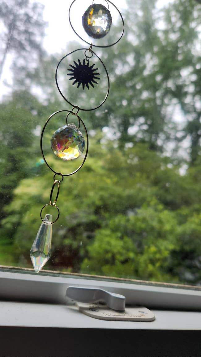 Hanging prima   catcher with crystal prisms and a prima   motif, displayed connected  a window, with a blurred greenish  outdoor presumption    successful  the background