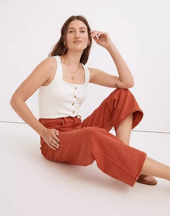 a model sitting on the floor wearing rust-colored wide jeans