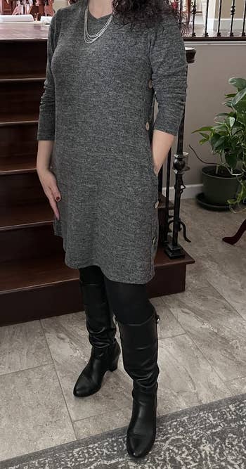 a reviewer wearing the dress in gray over black leggings and knee-high boots 