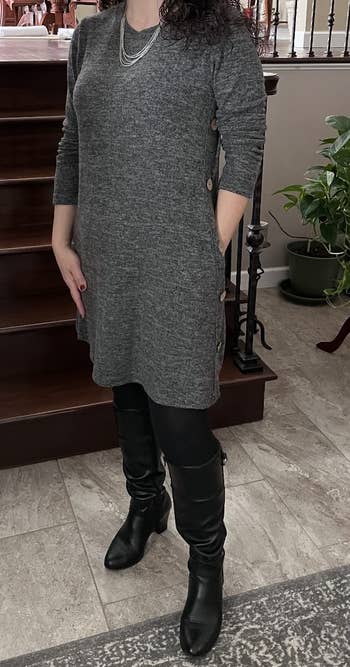 a reviewer wearing the dress in gray over black leggings and knee-high boots 