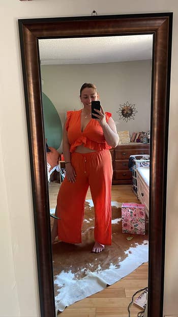 reviewer taking picture in the mirror wearing outfit in orange