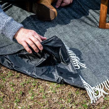 lifestyle photo showing the waterproof underside of faux wool picnic blanket