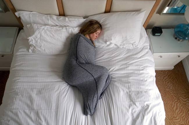 Model encased in gray sleep pod on a bed 