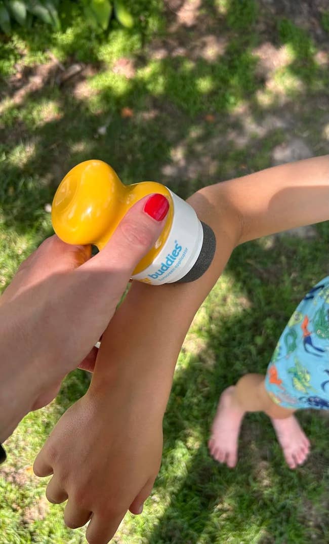 Applying sunscreen instrumentality to a child's limb outdoors, showcasing an easy-to-use skincare product