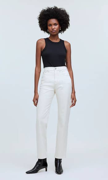 Model wearing a sleeveless top with high-waisted white jeans and black boots