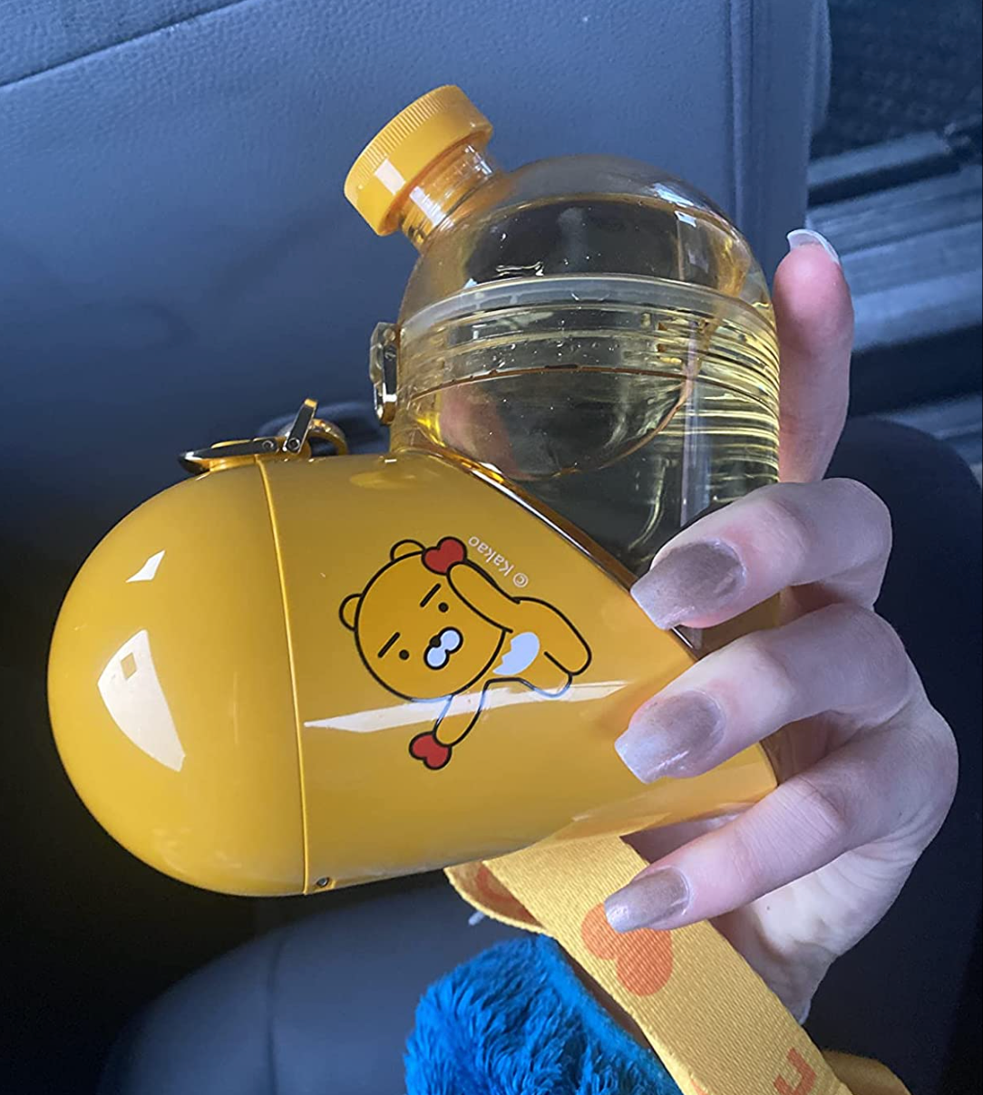 Reviewer holding yellow heart shaped container with one solid side for snacks and a clear side for water 