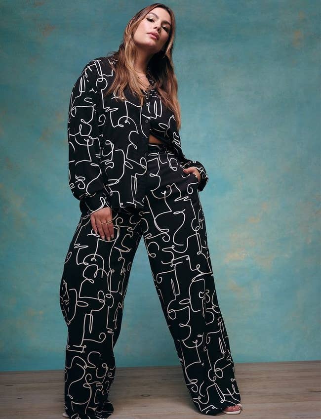 A model posing in a black set with abstract faces all over