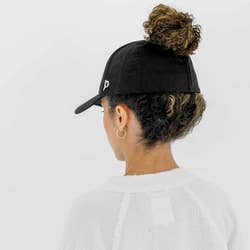 view from behind of a model wearing the hat in black with their hair in a high ponytail