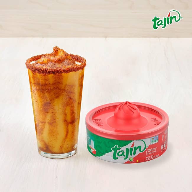 a rimmed glass next to the flat round container of tajin