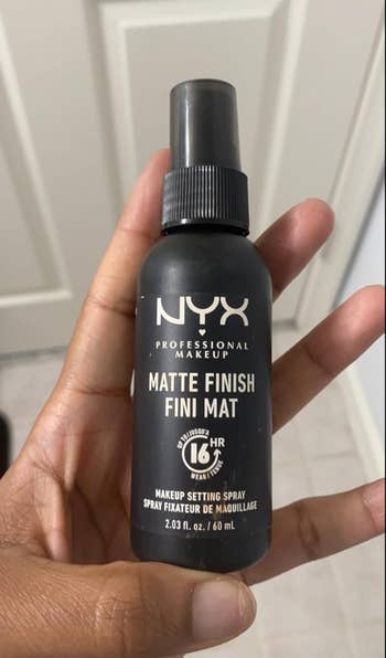 Person holding a NYX Professional Makeup Matte Finish Setting Spray bottle, 2.03 fl oz, in a shopping context